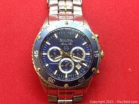 Front view of watch face showing blue dial, subdials, rotating bezel, Bulova logo, Marine Star and 100M markings, scratch on crystal