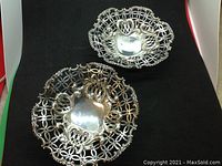 Pair of two footed openwork silver dishes displayed on black background