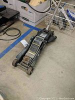 Side angle photo of the black Craftsman floor jack on the floor showing overall condition and wheels.