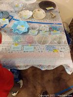 Overview of the vintage Fenton art glass collection including several clear and ruffled dishes as well as some hand-painted items grouped on a quilted surface