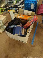 Photo showing cabinet liners, plastic wrap, foil, and some black plastic items in a box.