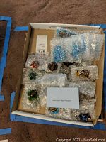 Box containing approximately 10 individually bubble-wrapped hand-blown glass pendants of assorted shapes and colors.