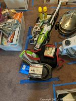 Wide shot showing Bissell Crosswave vacuum mop with cleaning sprays, shoe shining kit, and other cleaning supplies on the floor.