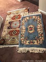 Two Persian-style rugs on floor; one larger with geometric pattern, one smaller with blue floral design.