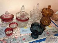 View of all vintage Indiana glass candy dishes arranged together showing variety of styles, colors and lids included.