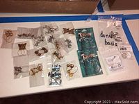 Overview photo of charm holders and donut bails, several parts in plastic bags including butterfly and loop designs and packaged tokens.