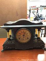 Front view of the vintage mantle clock showing Adamantine finish, cream-colored columns, ornate dial, and claw feet.