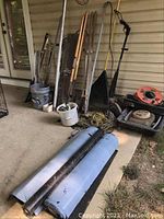 Photo showing electric edger, shovels, rake, digging fork, post hole digger, bulb placer, and bundled cords.