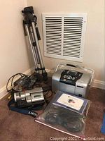 Overall lot showing the Epson photo printer, Sony Handycam camcorder with strap, and tripod leaning against a wall on carpet.