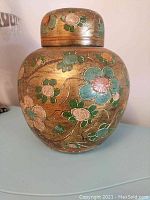 Photo showing front side of the hand painted Italian pottery vase with lid, floral patterns in green, orange, pink on brown background.