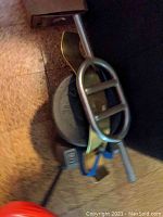 Weight plates, dumbbells, and triceps bar partially stacked on floor and red chair.