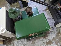 Overview showing two large green Coleman propane camp stoves stacked with a green Coleman gas lantern on top.