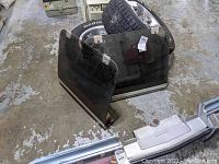 Two tinted hatch tops with metal mounting brackets and chrome rear bumper, displayed leaning against vehicle tires on concrete floor.