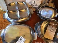 Photo showing the grouped serving pieces including a divided serving tray, various serving trays, nested bowls, and a silver duster bag in the background.