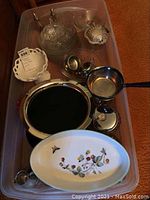 Overview of all items including dessert plates, serving platter, creamer, sugar bowl, candy dish, chafing dish, salt and pepper shakers, trivet, and ashtray placed together in a plastic bin.