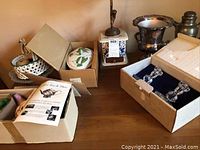 Lot displayed on wooden surface showing lamp, champagne bucket, covered serving dish, coffee and tea set and decorative fruit.