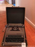 Full front view of the Smith-Corona typewriter open in its carrying case showing keyboard and carriage.