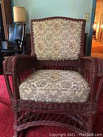 Full front view of wicker rocking chair with floral upholstery showing seat and back cushion design.