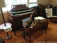 Wide shot of the Hammond A-102 organ with wood bench and sheet music on wooden table nearby.