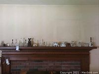 Wide shot of decorative items on mantel including various ceramic and crystal bells and figurines spaced evenly.