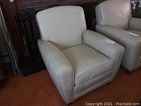 Front angle view of two cream leather club chairs placed side by side