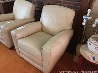 Pair of beige leather club chairs positioned in front of brick hearth