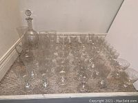 Full set of assorted vintage crystal glassware including decanter, vinegar cruet, and multiple glasses arranged on floor