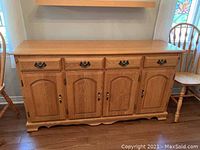 Front view of the honey oak dining room hutch showing four drawers and four cabinet doors with metal hardware.