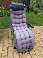 Front view of patio gravity chair with tufted light purple cushion and darker purple headrest.