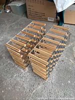 Two wood and metal wine racks side by side on a concrete floor, showing their size and structure.