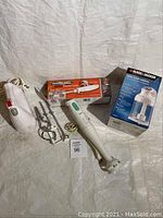 Photo of Braun mixing wand, Black & Decker 3-cup chopper box, Proctor Silex electric knife box, and white handheld mixer with attachments laid out on a light background