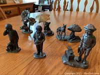 Photo showing all six pewter figurines on a wooden table arranged in two rows.