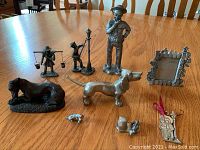 Overview of all figurines and frame on wooden table.