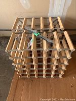 Photo of one of the two wood and metal wine racks showing the 5 by 5 bottle slots and stacking connectors on top.