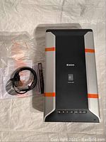 Canon CanoScan 5600F scanner top view with cables and documentation beside it.