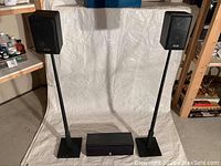 Photo of two KLH 970A bookshelf speakers mounted on stands next to Cerwin Vega CC-240 center speaker placed on floor against shelf
