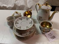 Full set of German porcelain hot chocolate set including cups, saucers, side plates, creamer, sugar bowl, and pot displayed on table.