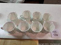 Top-down view of eight white Royal Grafton bone china coffee mugs arranged in two rows on a white surface.