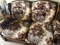 Front view of the two-seater love seat showing original patterned upholstery with pastoral scenes in browns and beiges, wooden frame, and cushion details.