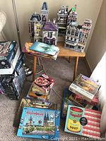 Multiple Wrebbit 3D puzzles assembled on tables and floor alongside boxed puzzles and 7 CS Lewis CD book sets.