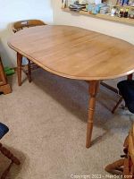 Maple dining table viewed at an angle showing its wood grain and turned legs.