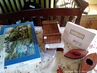 Photo showing a rectangular wooden puzzle box shaped like a barrel with sliding panels, a puzzle box instruction booklet, and a puzzle box packaging.
