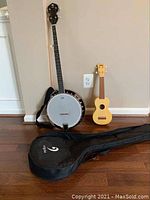Banjo and ukulele placed against a wall with the banjo case in front