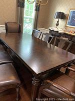 Full view of rectangular dining table set up in room with chairs.