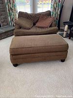 Front view of brown chair and ottoman with pillows, showing overall condition.