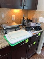 Countertop view showing all items: panini press, cutting boards, kettle, blender unit, personal blender, towel holder