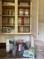 View of shelves containing clear plastic food storage containers, measuring cups and pitchers, gloves boxes, and lids.