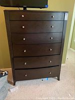 Front view of tall dresser showing all five drawers and metal knobs