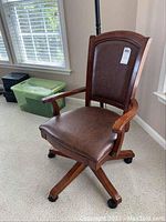 Full view of the chair showing wood frame, leather padded seat and backrest, and armrests.