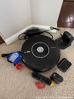 Two iRobot Roomba Pet Series 595 robotic vacuums with charging docks, power adapters, replacement brushes, and filters on carpeted floor.